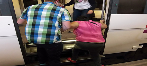 Un mujer tiene que ser ayudada por otro usuario a subir al vagón del tren