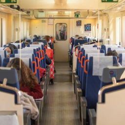 Interior de un tren con pasajeros utilizando mascarillas