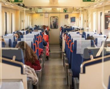 Interior de un tren con pasajeros utilizando mascarillas