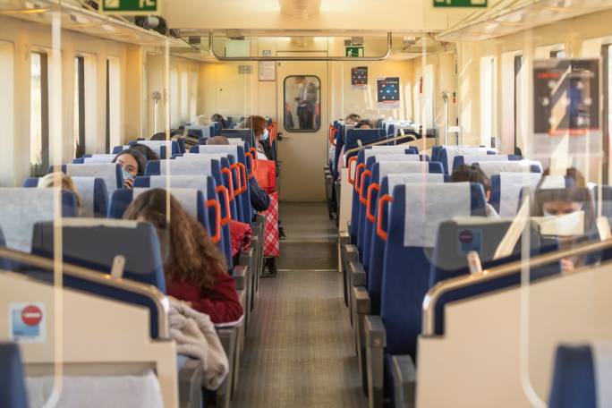 Interior de un tren con pasajeros utilizando mascarillas