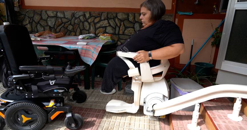 Persona en silla de ruedas trasladándose a una silla adaptada, en un entorno que refleja accesibilidad y mejoras en la movilidad para personas con discapacidad.