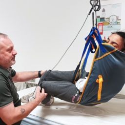 Auxiliar de geriatría ayudando a una usuaria en un centro de día, parte de un curso de formación