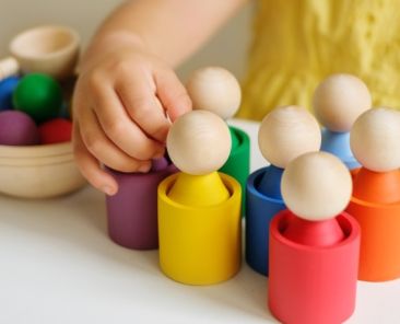 Manos de una niña jugando con piezas de madera en un juego inclusivo