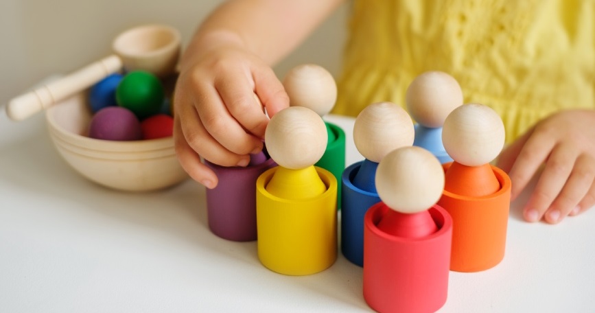 Manos de una niña jugando con piezas de madera en un juego inclusivo